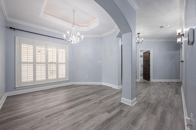 unfurnished dining area with arched walkways, a notable chandelier, a tray ceiling, and wood finished floors