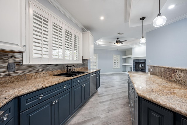 kitchen with blue cabinets, ornamental molding, a sink, a tray ceiling, and ceiling fan