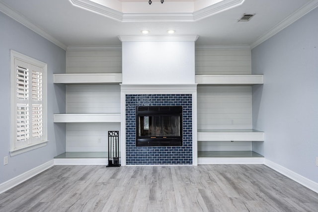 unfurnished living room featuring a healthy amount of sunlight, wood finished floors, visible vents, and ornamental molding