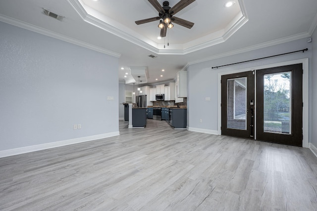 unfurnished living room featuring visible vents, a ceiling fan, a tray ceiling, and ornamental molding