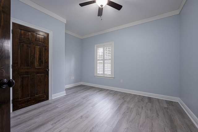 spare room featuring crown molding, wood finished floors, baseboards, and ceiling fan