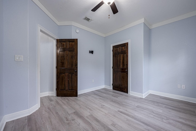 unfurnished bedroom with a ceiling fan, visible vents, wood finished floors, baseboards, and ornamental molding