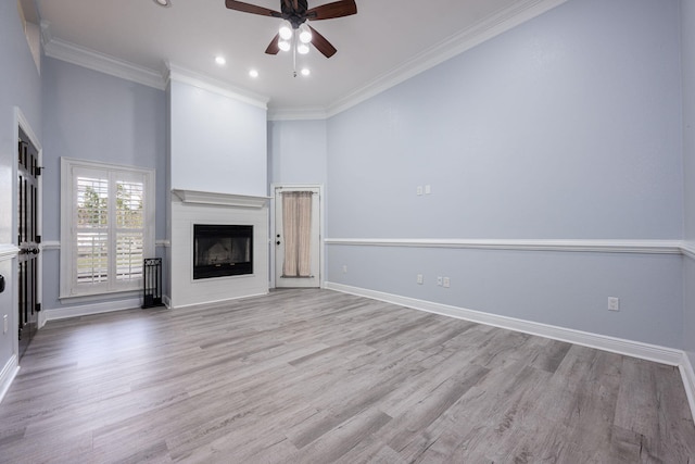 unfurnished living room with wood finished floors, baseboards, a fireplace, ornamental molding, and ceiling fan