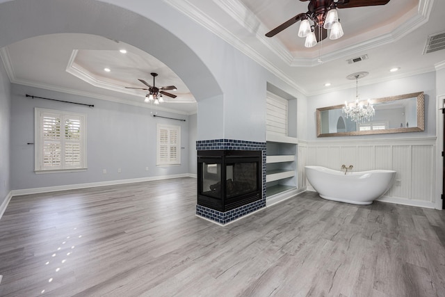 living area with visible vents, ceiling fan with notable chandelier, a tray ceiling, and built in features