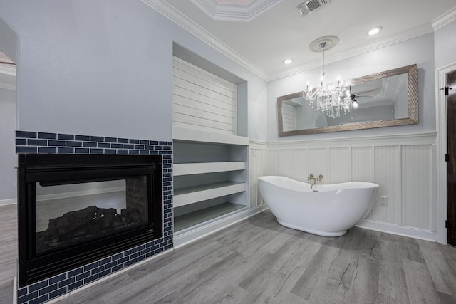 bathroom with wood finished floors, visible vents, a soaking tub, a multi sided fireplace, and ornamental molding