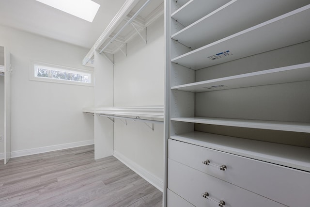 walk in closet with light wood-style floors and a skylight