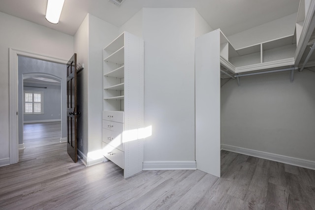 spacious closet featuring arched walkways and wood finished floors