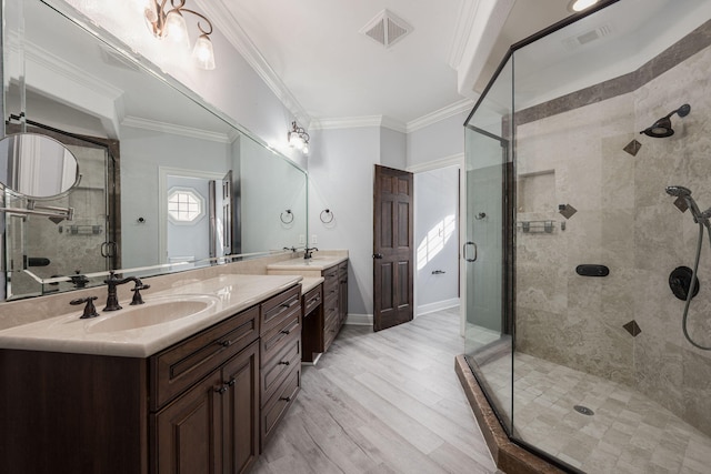 bathroom with visible vents, ornamental molding, a shower stall, and a sink