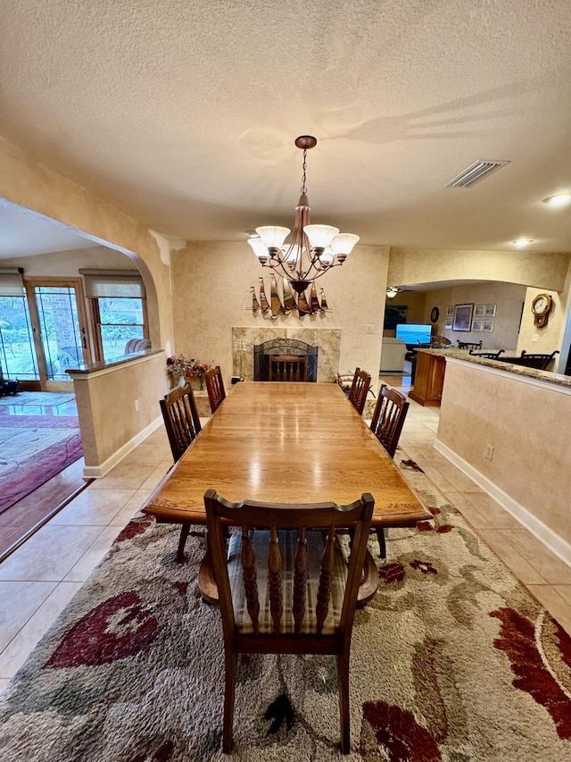 dining area with arched walkways, visible vents, a notable chandelier, and light tile patterned floors