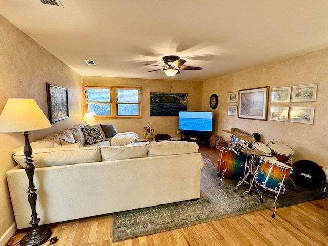 living area featuring ceiling fan, visible vents, and wood finished floors