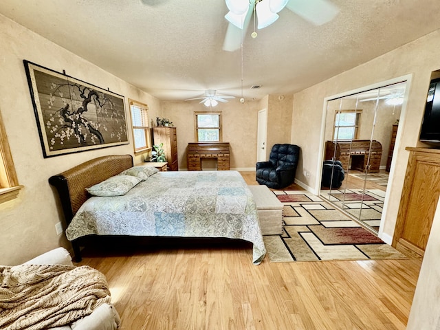 bedroom featuring ceiling fan, baseboards, a textured ceiling, and wood finished floors