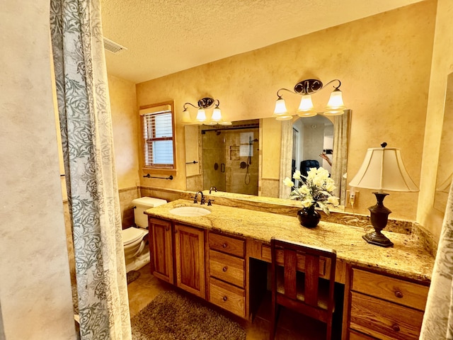 full bath with vanity, a shower stall, a textured ceiling, toilet, and a textured wall