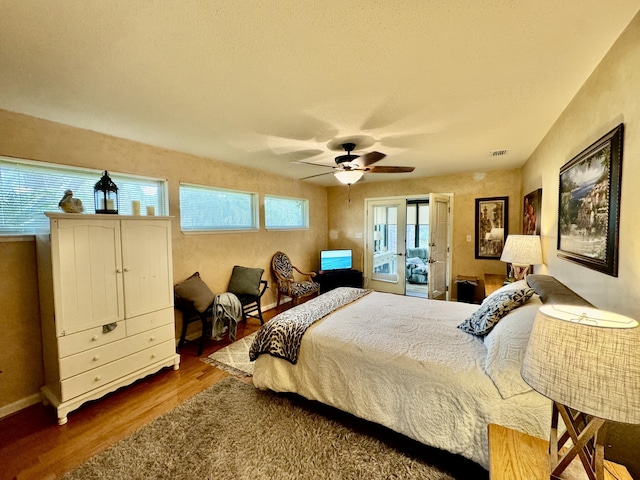 bedroom featuring access to exterior, wood finished floors, visible vents, and ceiling fan