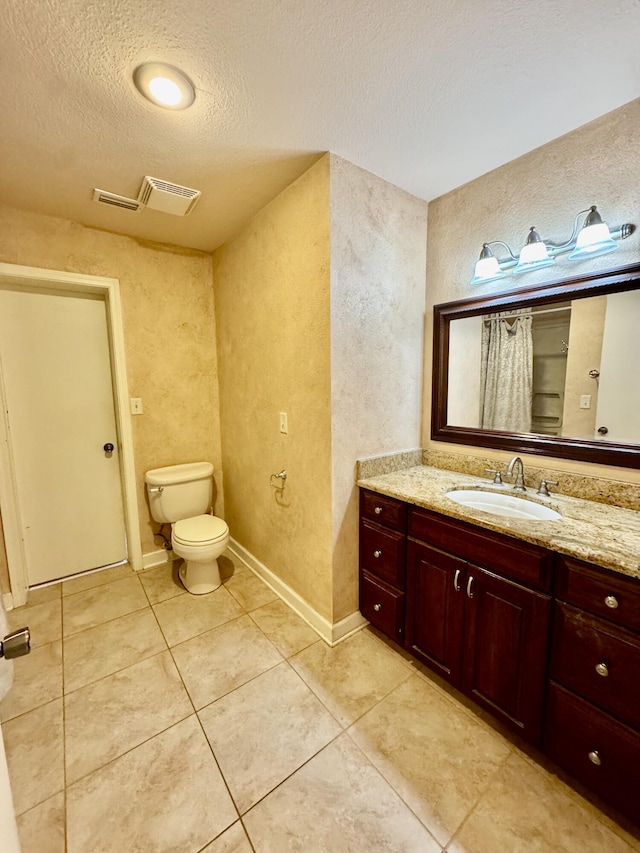 full bath featuring tile patterned flooring, toilet, vanity, a textured wall, and a textured ceiling