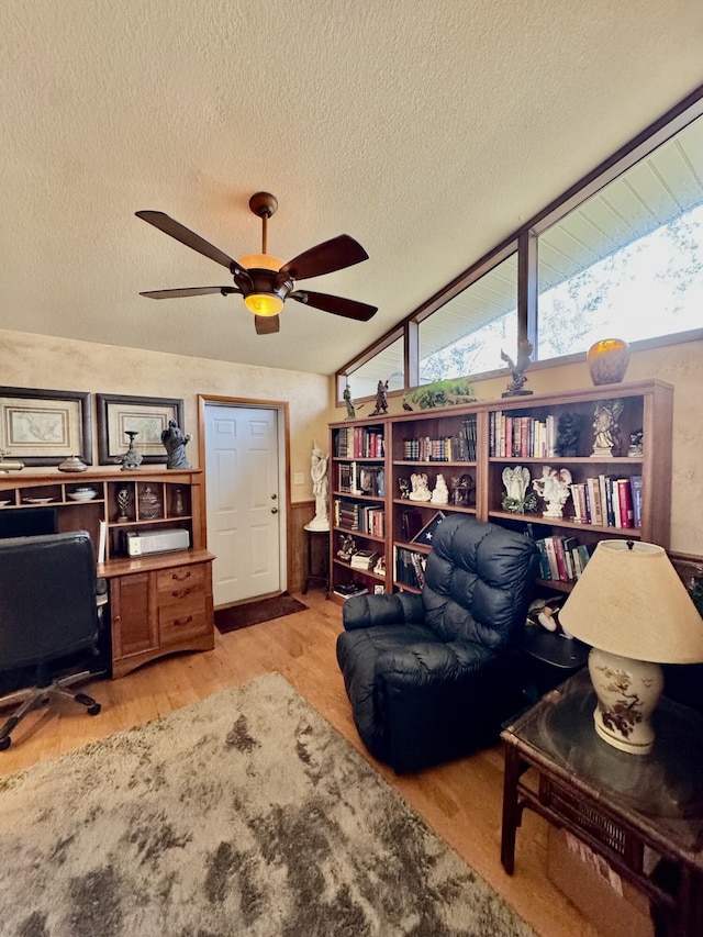 office with a wainscoted wall, wood finished floors, a textured ceiling, and ceiling fan