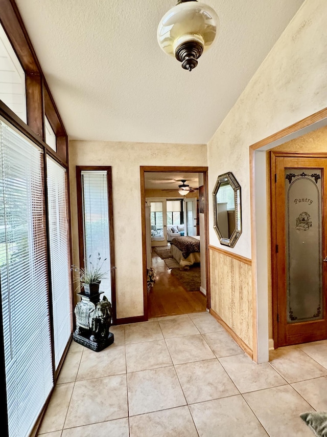 hallway with lofted ceiling, light tile patterned floors, and a textured ceiling