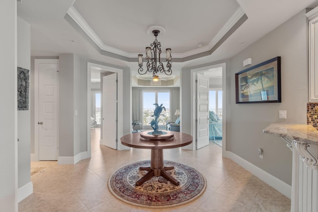 interior space with crown molding, baseboards, light tile patterned floors, a notable chandelier, and a raised ceiling