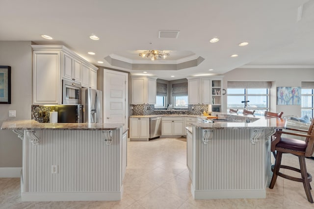 kitchen with visible vents, a raised ceiling, appliances with stainless steel finishes, and a peninsula