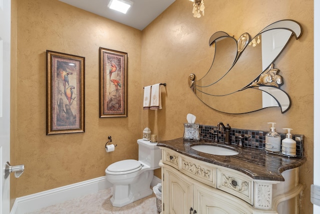 half bathroom with tile patterned floors, toilet, vanity, and baseboards