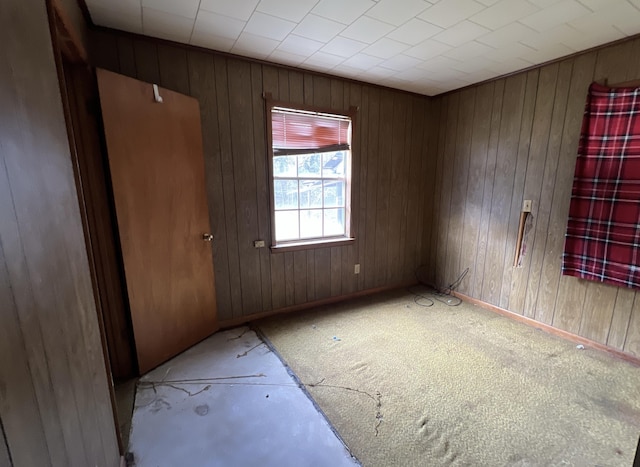 unfurnished room featuring wood walls and baseboards