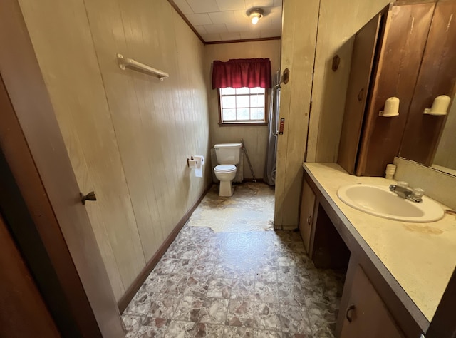 bathroom with wooden walls, crown molding, vanity, and toilet