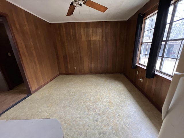 empty room featuring wood walls, baseboards, and ceiling fan