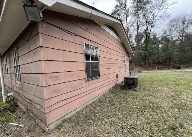 view of side of home featuring central air condition unit and a lawn