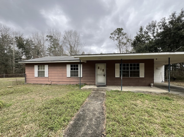 ranch-style home featuring an attached carport, a front yard, and fence