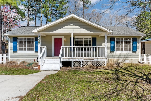 view of front of property featuring a porch, fence, a front yard, and roof with shingles