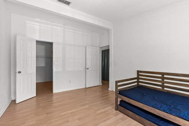 bedroom with a spacious closet, visible vents, baseboards, and light wood-style floors