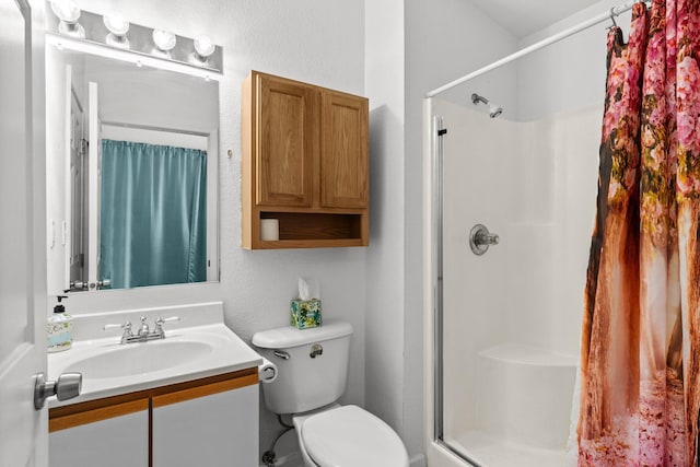 bathroom with a stall shower, toilet, vanity, and a textured wall