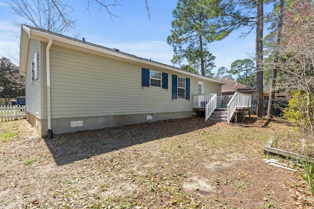 rear view of property with crawl space, a deck, and fence