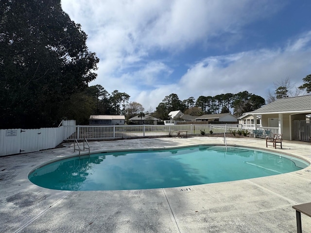 community pool with a patio and fence