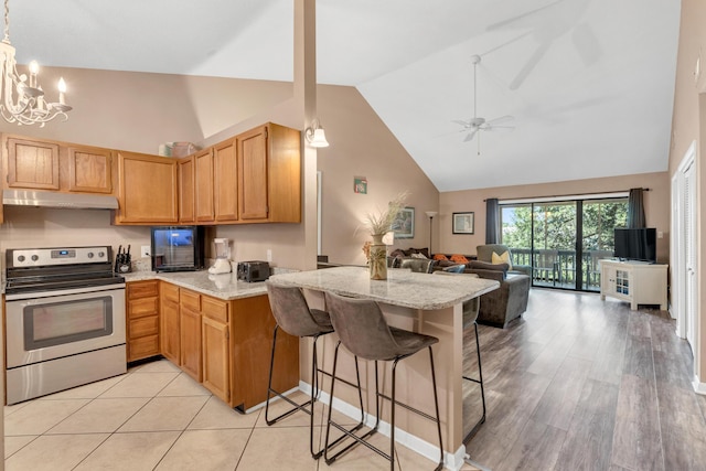 kitchen with stainless steel electric range oven, light stone counters, a peninsula, under cabinet range hood, and open floor plan