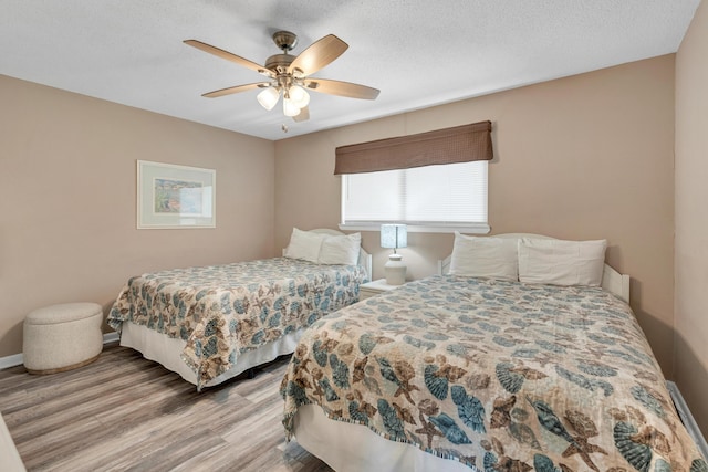 bedroom featuring a ceiling fan, wood finished floors, baseboards, and a textured ceiling