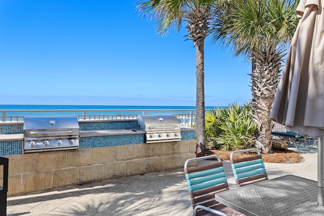 view of patio / terrace with a water view, a grill, and exterior kitchen