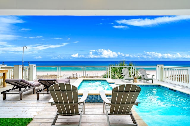 view of pool featuring an in ground hot tub, a deck with water view, and a view of the beach