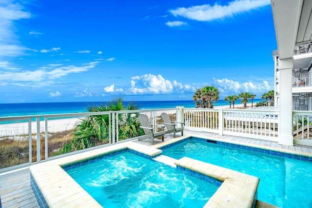 view of pool with a pool with connected hot tub, a view of the beach, and a water view