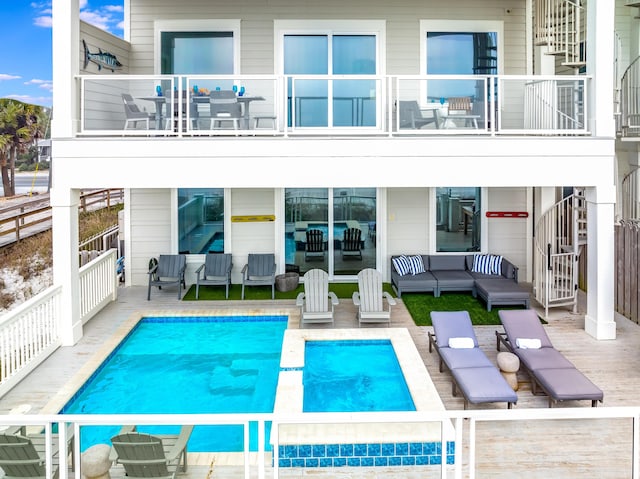 back of property featuring a patio area, an outdoor pool, outdoor lounge area, and a balcony