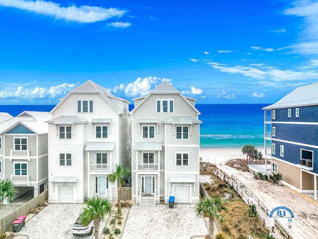 view of front of house featuring a view of the beach, decorative driveway, a water view, and an attached garage