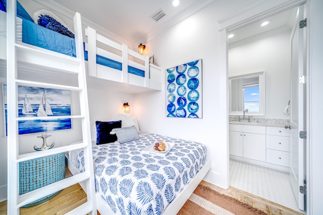 bedroom with light tile patterned floors, visible vents, ensuite bath, recessed lighting, and a sink