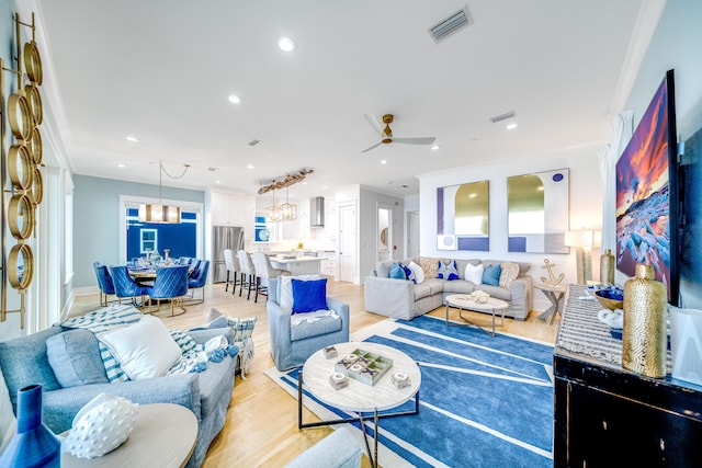 living room with visible vents, light wood-style flooring, recessed lighting, ornamental molding, and ceiling fan