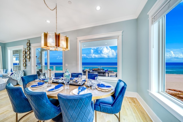 dining area featuring light wood-style flooring, crown molding, and baseboards