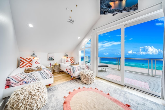 bedroom featuring visible vents, a water view, vaulted ceiling, wood finished floors, and access to outside