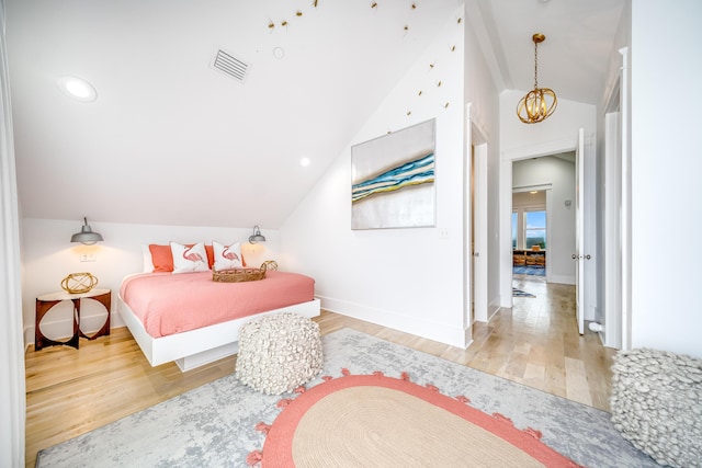 bedroom featuring visible vents, baseboards, vaulted ceiling, an inviting chandelier, and wood finished floors