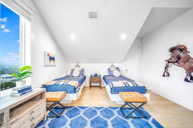 bedroom with visible vents, baseboards, lofted ceiling, and wood finished floors