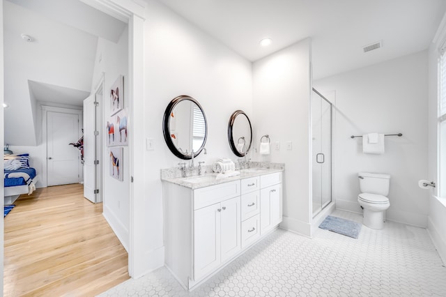 ensuite bathroom featuring visible vents, double vanity, a sink, a shower stall, and toilet