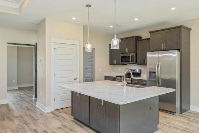 1517 Kais St, Baker, FL 32531 - kitchen with a barn door, dark brown cabinets, a sink, light wood-type flooring, and appliances with stainless steel finishes