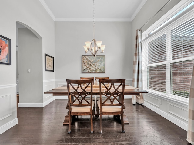 dining space featuring arched walkways, ornamental molding, a decorative wall, and dark wood finished floors