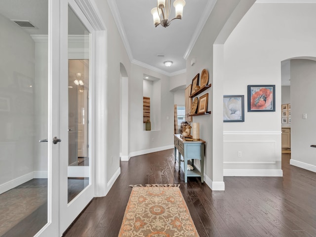 entryway featuring visible vents, arched walkways, an inviting chandelier, dark wood-style floors, and crown molding